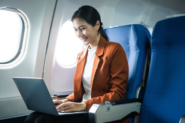 A woman in a formal suit sits in a window seat of an economy class section, looking out the airplane window, ready for her business journey.