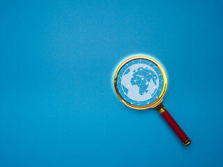 Magnifying glass with networked globe on blue background.