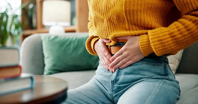 Stomach, pain and woman hands in home with abdomen, belly and sick from constipation or menstruation. Bloating, living room and couch with nausea and virus in lounge with health problem and issue