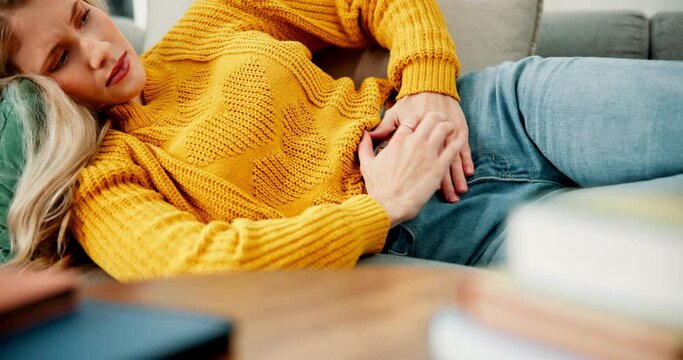 Woman, tummy ache and pain with cramp on sofa in menstruation, constipation or gastro at home. Frustrated female person with diarrhea, reflux or abdomen injury from digestion issue or stomach virus