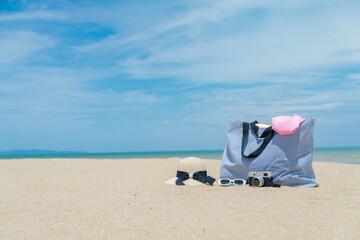 Suitcase with beach accessories on sand, hat, sunglasses, camera, sea and sky background. summer...