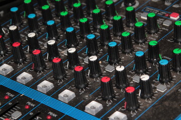 Close-Up View of an Audio Mixer with Numerous Knobs and Controls