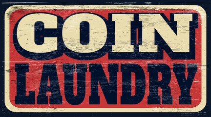 Aged and worn coin laundry sign on wood