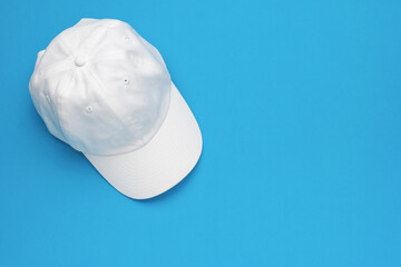 White Baseball Cap on Blue Background: Minimalist Fashion Accessory Stock Photo