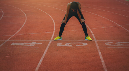 Tired woman runner resting, take a breath at the race track.