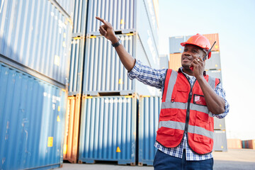 African factory worker or engineer using walkie talkie and talking about work in containers...