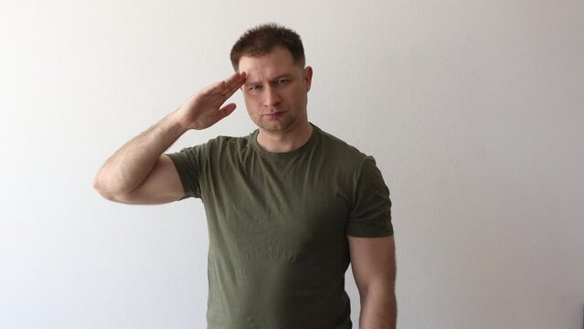 A man in a military hacky sack t-shirt salutes with his hand. 