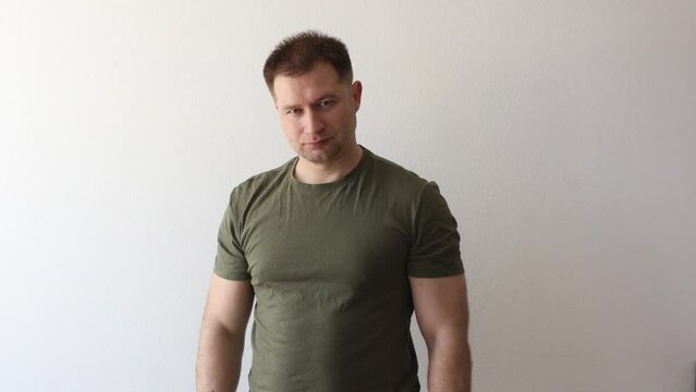 A man in a military hacky sack t-shirt salutes with his hand. 