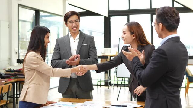 Group of Asian businessmen discussed and presented graphs of business work. The team applauded to show goodwill in the conference room.
