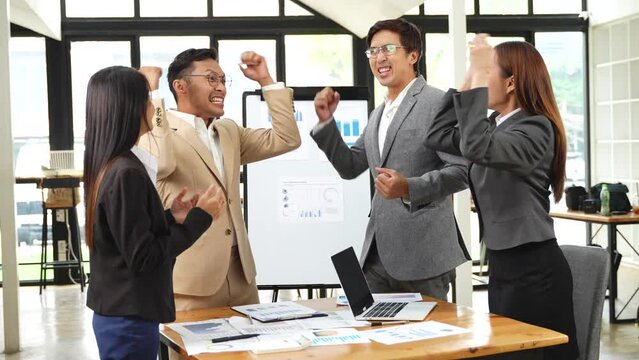 Group of Asian businessmen discussed and presented graphs of business work. The team applauded to show goodwill in the conference room.