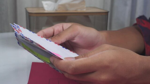 close up of hands sorting envelopes on table with red document folder