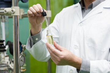 close up scientist testing and holding cannabis cbd oil bottle in chemical laboratory