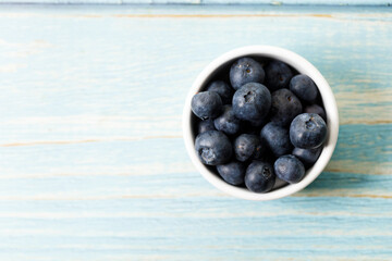 Ripe organic blueberries on blue wooden table background. Selective focus.