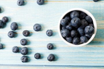 Ripe organic blueberries on blue wooden table background. Selective focus.