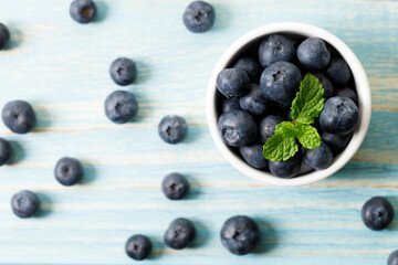 Ripe organic blueberries on blue wooden table background. Selective focus.