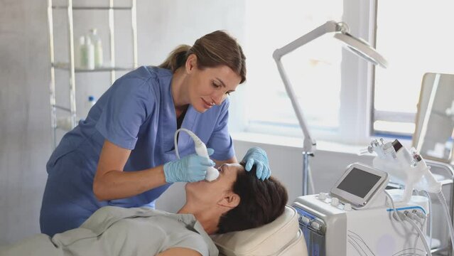 Woman doctor doing a facial deep hydration procedure on elderly female pacient in aesthetic medicine clinic. High quality 4k footage