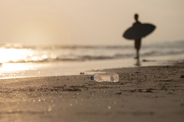 Waste plastic bottles that will be brought to the beach by waves, silhouette of a boy practicing...