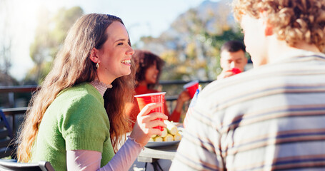 Friends, woman and laughing with drinks outdoor on terrace with conversation, reunion and social event in summer. People, barbecue and happy on patio with food, talking and celebration with bonding