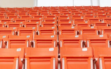 Fototapeta premium Line of orange sport seat grandstand in an empty stadium.