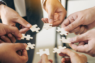 The concept of teamwork and partnership. Businessman's hands putting together puzzle pieces in the office and join together in a jigsaw puzzle team. Charity. Volunteers. Business unity as a team.