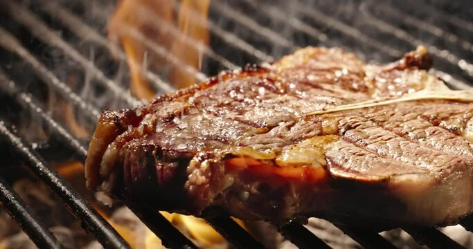 Smooth movement. Golden crusted mouth watering T-bone steak is sprinkled with coarse salt and finished on grill. Juicy, flavorful masterpieces that are meat lover's dream come true, template for title