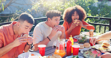 Friends, group and eating hamburger outdoor on terrace with hunger, reunion and social event in summer. People, barbecue and lunch on patio with food, diversity or celebration with bonding and drinks