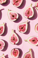 Figs arranged in a pattern on light pastel pink background. Summer fruit aesthetic.