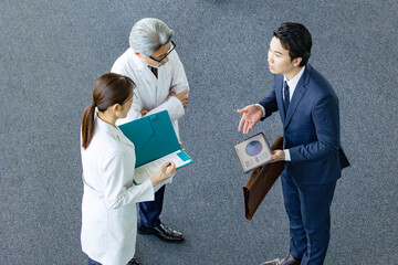白衣の技術者に説明するビジネスマン