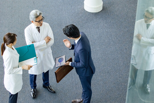 白衣の技術者に説明するビジネスマン