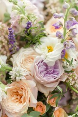 bouquet of mixed flowers including lavender, peach, and white blossoms, with green foliage