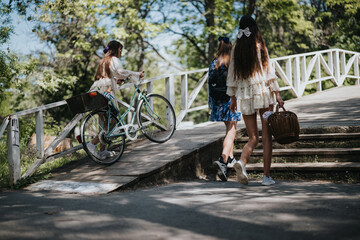 Fototapeta premium Three young girls walking together in a park on a sunny day, one holding a picnic basket, and another riding a bicycle.