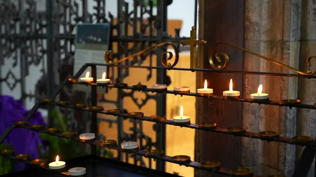Several small lit wax candles flickering in St Davids Cathedral, Wales