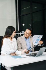 Two business workers talking on the smartphone and using laptop at the office..