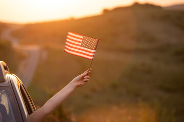 Woma in the car holding a waving american USA flag.