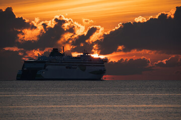 A cruise ferry sails beyond the sea horizon at sunset in the Baltic Sea.