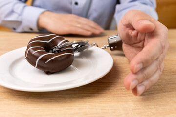 A man is handcuffed to a chocolate donut. Passion for sweets.