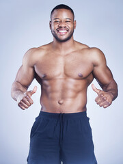 Fototapeta premium Fitness, portrait and happy black man with hand pointing to body in studio for training, wellness or abs progress on grey background. Sports, face and athlete show sixpack, growth and muscle flex