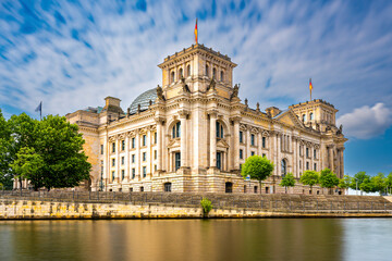 Obraz premium Reichstagsgebäude in Berlin, im Vordergrund die Spree, leicht bewölkter blauer Himmel, horizontal, Langzeitbelichtung