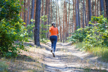Fototapeta premium young girl on a morning run in a sunny pine forest