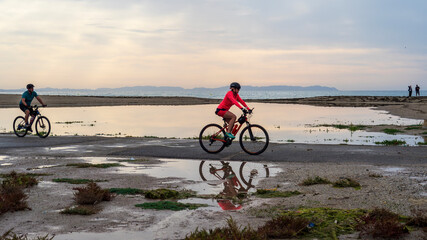 Ciclistas paseando por la orilla de la playa de Roquetas de Mar al amanecer