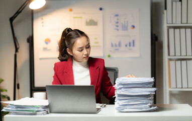 Close-up of businesswoman hands holding a pile of paperworks, sitting near the stack of documents and writing down important analytics report. Financial