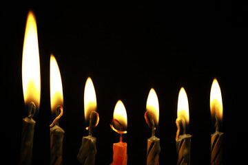 Lit Candles in a Row Against a Dark Background Emitting Warm Glow