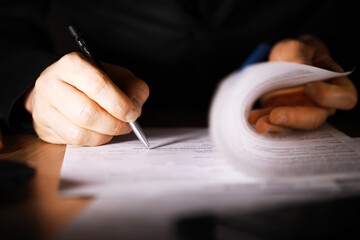 Businessman Signing Contract Document at Desk in Office Under Focused Lighting