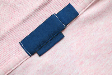 Blank blue laundry care clothes label on pink shirt fabric texture background