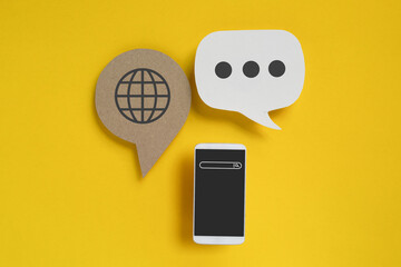 For online translation for foreign languages concept, top view of real brown and white paper cut and smartphone on grunge yellow background