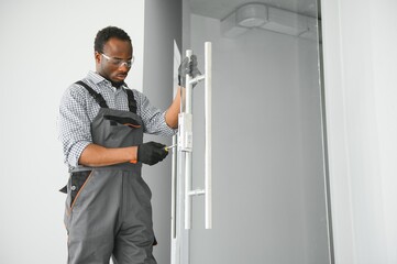 Worker installing glass door at office