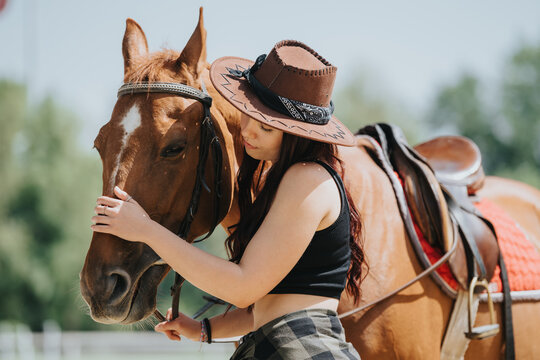 Young woman wearing a cowboy hat gently embraces a horse. The scene exudes warmth, affection, and a strong bond between human and animal. - Powered by Adobe