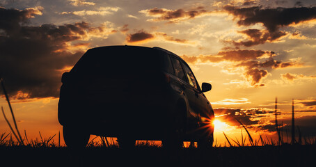 Silhouette of a car in sunset on countryside dirt road with dramatic sky in background