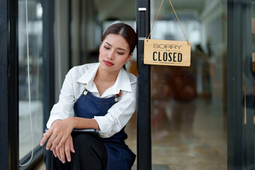 An Asian female barista is stressed and bored as the economy has decreased coffee shop sales, causing the store to close. The impact of startup ideas for small businesses.