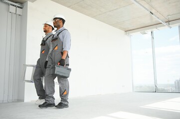 multicultural builders in hardhats at construction site